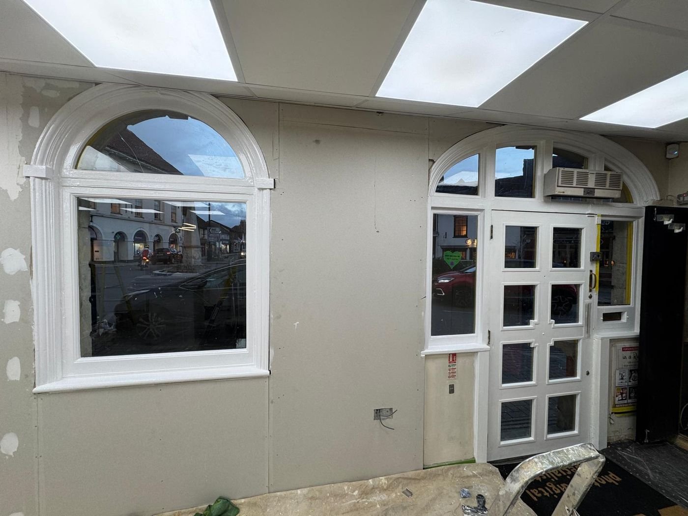 Shop entrance after work: white arched door and window with new ceiling