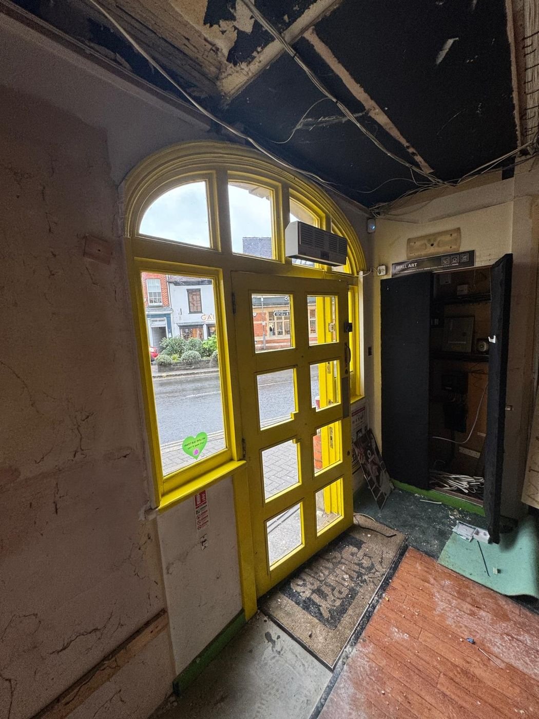 Shop entrance before work: yellow arched door with exposed ceiling